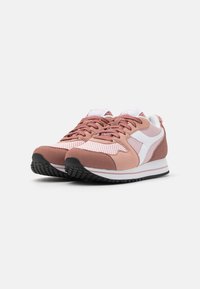Scarpe sportive rosa realizzate con una combinazione di materiali suede e mesh, con un logo bianco, lacci texture e una suola in gomma nera.
