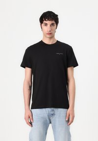 Schwarzes Baumwoll-T-Shirt mit Rundhalsausschnitt und kurzen Ärmeln, mit einem kleinen Logodruck auf der Brust und einer lockeren Passform.
