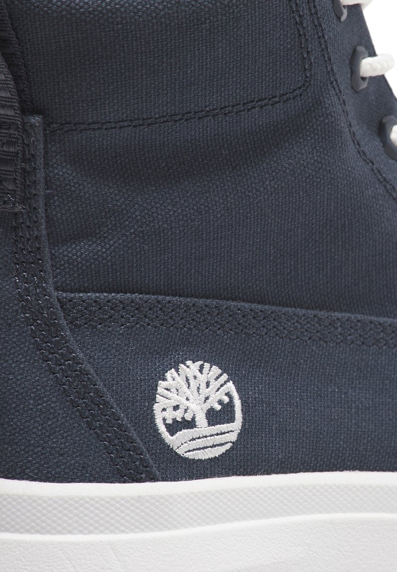 Marineblaue Canvas-Hochschuh-Sneaker mit weißem Logo, texturiertem Material, weißen Schnürsenkeln und einer kontrastierenden weißen Gummisohle.