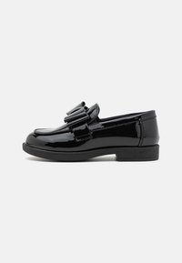 Must mustast nahast loafer, mille esiosas on dekoratiivne paelte detail, madal ploki konts ja sile läikiv pind.