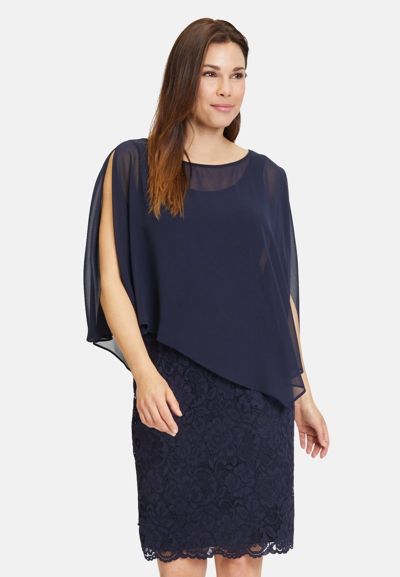 Námořnické šaty s vrstveným průhledným kabátem na vrchu, zdobené květinovou krajkou na okraji sukně. Hladká textura a elegantní splývání.