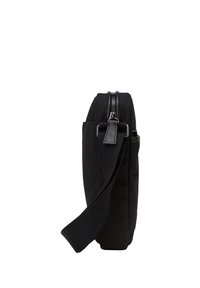 Borsa nera in tela con una texture liscia, chiusura con zip, tracolla regolabile e tasca laterale. Forma rettangolare, design compatto, stile minimalista.