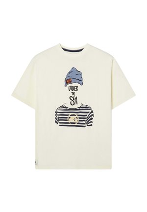 Camiseta crema con un gráfico de una persona con un gorro azul y una camisa de rayas horizontales con el texto "BAJO EL MAR". Manga corta.