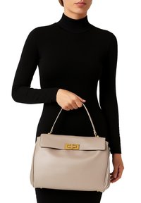 Borsa a mano in pelle beige con design strutturato, chiusura in oro e manico superiore. Texture liscia con eleganti pieghe laterali.