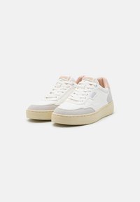 Zapatillas blancas y grises con parte superior texturizada, collar acolchado y suela de goma beige. Presenta cordones y el logotipo de la marca en la lengüeta.