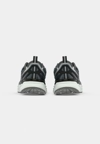 Chaussures de sport noires et grises avec un design texturé, dotées d'une semelle rembourrée, d'une languette et d'accents réfléchissants à l'arrière.