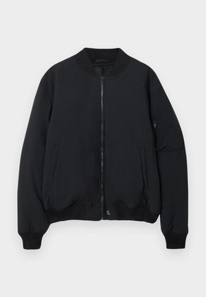 Juodas bomberiai su užtrauktuku, apvaliu kaklu, raštuotais rankogaliais ir apatine dalimi. Yra šoninės kišenės ir naudingos kišenės kairiajame rankovėje.