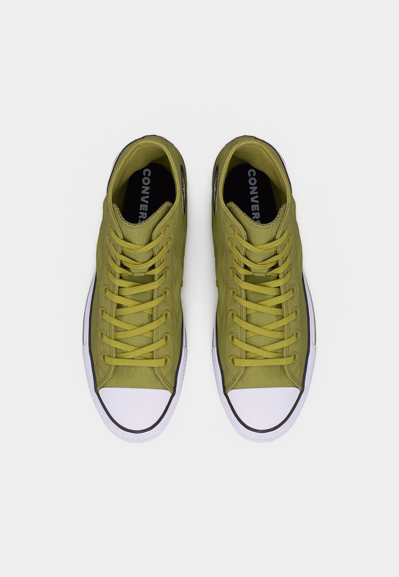 Par de zapatillas Converse de caña alta en verde oliva vistas desde arriba, con punteras de goma blancas y suelas con borde negro sobre un fondo gris.