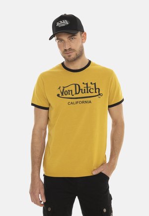 T-shirt en coton jaune avec des accents noirs et un logo imprimé « Von Dutch CALIFORNIA » sur la poitrine. Coupe décontractée, manches courtes.