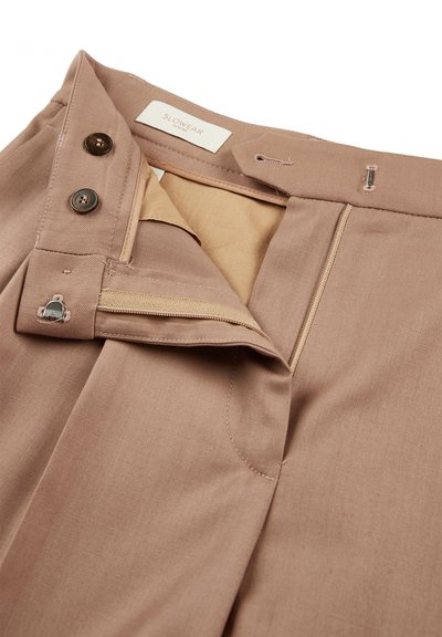 Khaki broek met een gladde textuur, voorzien van een rits, details van messingknopen, ton-sur-ton stiksels en een label aan de binnenkant van de tailleband.