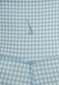 Tissu à carreaux bleu clair et blanc avec des coutures détaillées et un petit logo swoosh gris au centre.