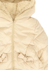 Beżowa pikowana kurtka z zamkiem błyskawicznym z przodu, podszewką z sztucznego futra w kapturze oraz dekoracyjnymi kokardkami w okolicy talii.