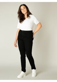 Zwarte denim broek met een slanke pasvorm, hoge taille en voorzakken, gecombineerd met een wit kort mouw T-shirt met V-hals en witte sneakers.