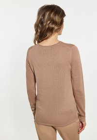 Pulover cu maneci lungi, de culoare maron deschis, textură linii, guler rotund, cu o margine curbată și mâneci mulate.