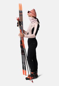Équipement de ski comprenant des skis gris et orange, un pantalon noir, un haut à manches longues rose, un chapeau assorti et un tour de cou, le tout maintenu avec des bâtons de ski.