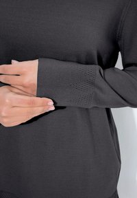 Maglione nero con polsino a coste e texture decorativa. La vista ravvicinata evidenzia i dettagli materiali e di design.