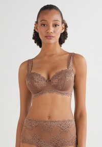 Brązowy biustonosz koronkowy z kwiatowymi wzorami, teksturowany materiał, szerokie wyściełane ramiączka, wsparcie druciane i falbany, w połączeniu z pasującymi figami.