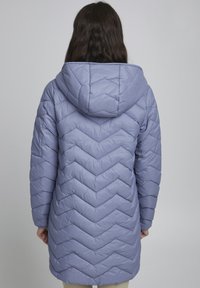 Giacca imbottita in lavanda chiaro, con cappuccio e un design a zigzag trapuntato. Tessuto liscio, maniche lunghe e taglio a lunghezza media.