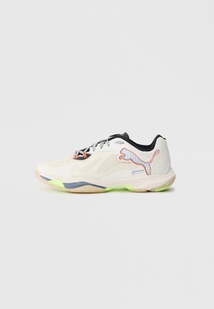 White athletic shoe with mesh and synthetic materials, black accents, orange detailing, and green sole. Features a Puma logo on the side.