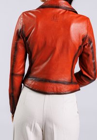 Rode leren jack met een getailleerd ontwerp, zichtbare stikdetails en een reliëflogo op de achterkant. Gladde textuur en op maat gemaakte silhouet.