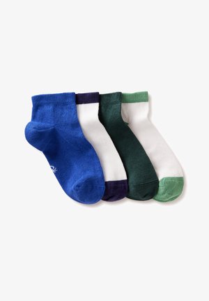 Vier paar enkelsokken in blauw, wit met marineblauwe teen, groen en wit met groene teen, naast elkaar gelegd op een witte achtergrond.