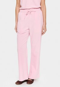 Light pink, loose-fitting pants made of soft fabric with an elastic waistband and drawstring. Features straight legs and minimal detailing.