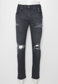Bleka svarta jeans i skinny fit, med slitna knäskärningar och fransade kanter. Klassisk design med fem fickor och metallbeslag.