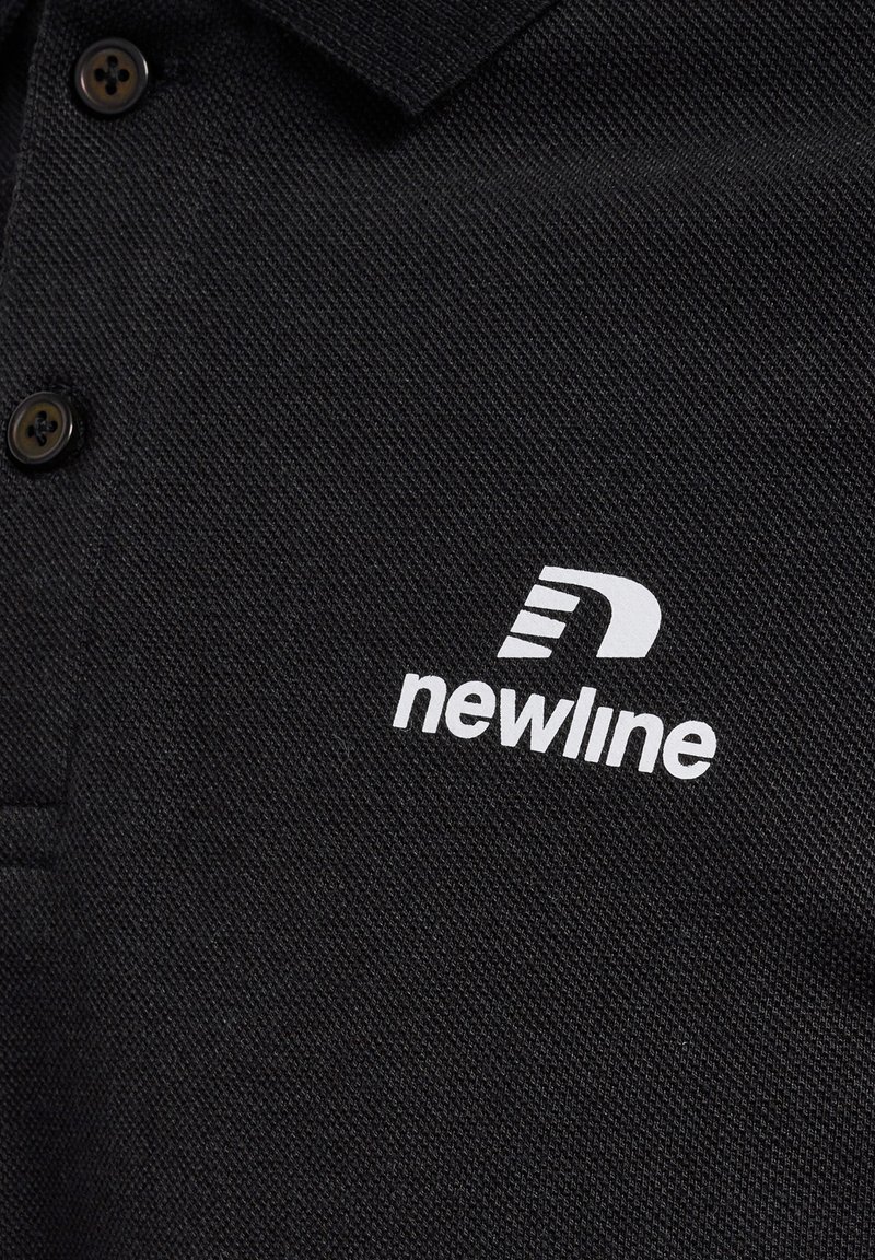 Polo noir avec un tissu texturé, deux boutons noirs et un logo imprimé blanc qui indique "newline" sur la poitrine gauche.
