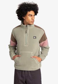 Fleece pullover in light green with brown, pink, and gray accents. Features a half-zip neck, kangaroo pocket, and textured fabric.