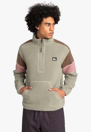 Fleece pullover in light green with brown, pink, and gray accents. Features a half-zip neck, kangaroo pocket, and textured fabric.