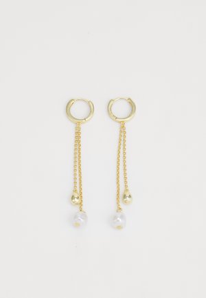 Boucles d'oreilles en or en forme de hoop avec une chaîne, mettant en avant des perles de culture blanches et un petit accent en or en forme de goutte. Texture métallique lisse, design épuré.