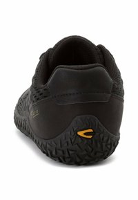 Baskets de sport noires avec un dessus en mesh, un talon texturé et une semelle en caoutchouc présentant une adhérence à motifs. Accent logo jaune sur le talon.
