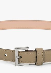 Béžový kožený opasek s hladkou texturou, s kovovou sponou stříbrné barvy a detailním prošíváním. Vnitřek je v světlejší béžové barvě.