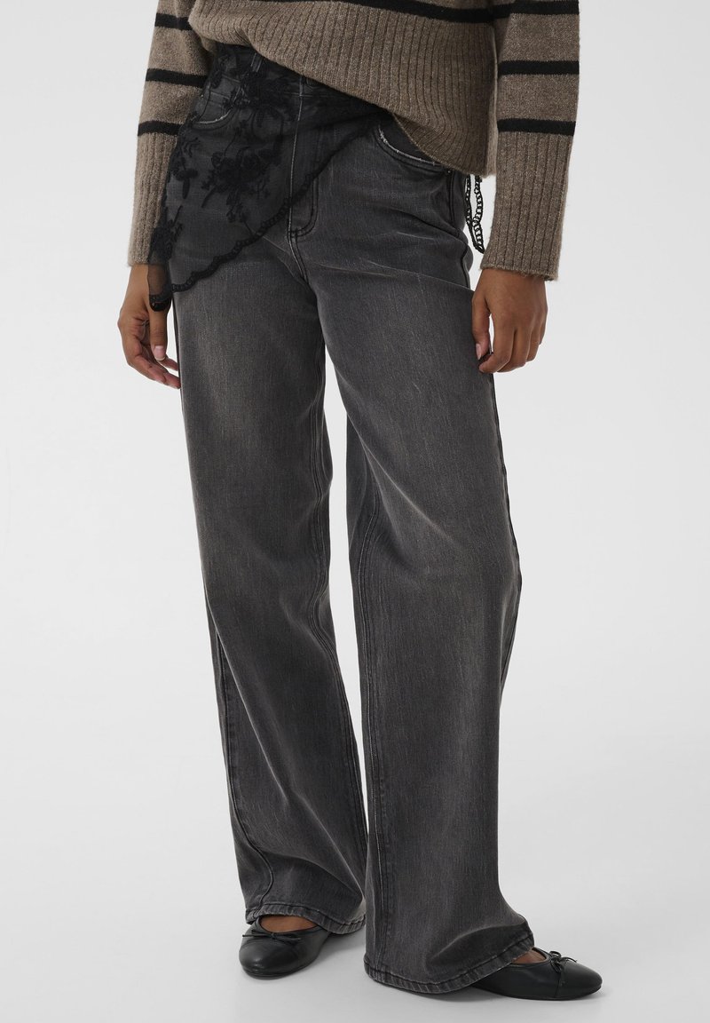 Bredde sorte jeans med en falmet vask, der har et gennemsigtigt sort blondeoverlay ved talje og detaljeret syning langs lommerne.