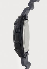 Montre numérique noire avec un bracelet en caoutchouc, boutons texturés, dos en acier inoxydable et un design de bracelet ondulé. Présente une finition lisse et mate.