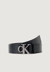 Zwarte leren riem met een gladde textuur, voorzien van een zilveren "CK" metalen gesp. Het design is stijlvol en minimalistich.