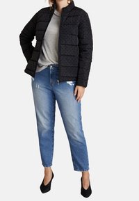 Black puff jacket with raised dots, gray top, light blue distressed jeans, and black pointed-toe heels. Fitted and tactile design.
