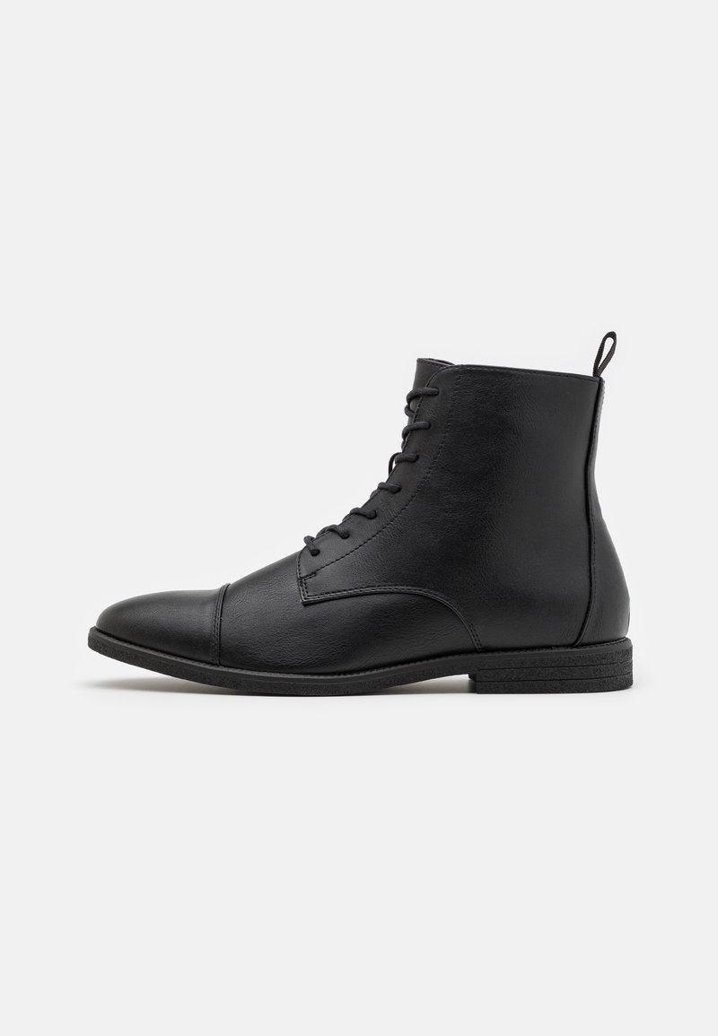Bottes noires pour cheville en cuir lisse, avec un bout arrondi, un laçage à l'avant et un petit talon. Boucle solide à l'arrière pour faciliter l'enfilage.