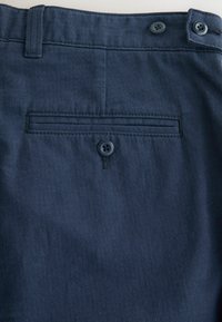 Navy blue pants fabric with a soft texture featuring a back pocket and two matching buttons at the waist, highlighting a clean, tailored design.