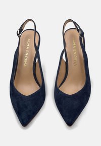 Talons slingback en suède bleu marine avec un bout pointu, présentant une bride de cheville et une semelle intérieure lisse beige avec un logo doré.