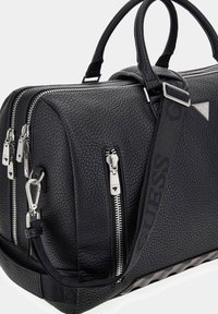 Borsa in pelle nera granulata con doppia cerniera, ferramenta argentata e tracolla staccabile con dettaglio logo. Manici arrotondati e base testurizzata.