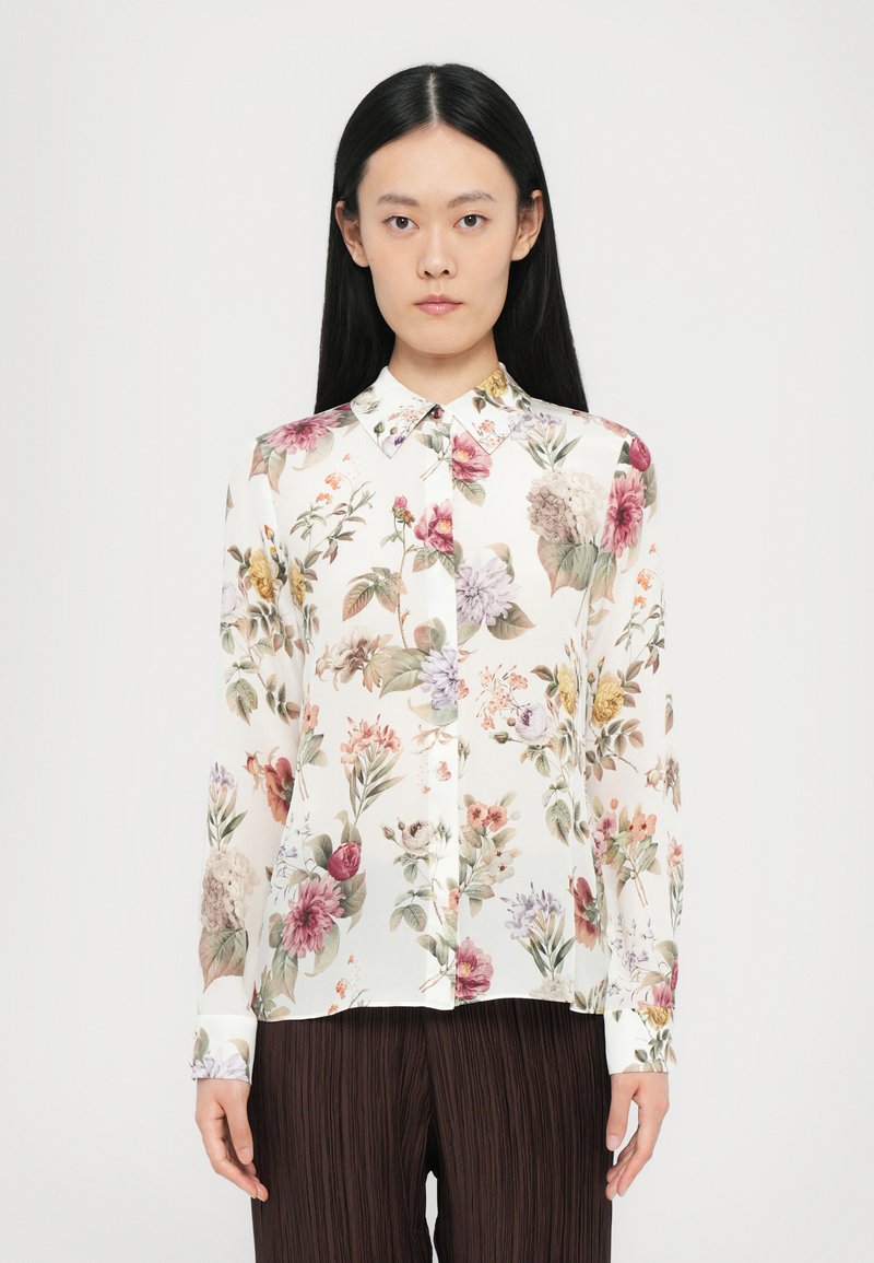 Langärmlige Bluse mit Blumenmuster auf weißem Hintergrund, mehrfarbigen Blumenmustern und einem klassischen Kragen. Weicher, leichter Stoff.