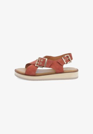 Sandale ouverte en daim rouge avec une semelle épaisse beige et deux boucles dorées sur la bride du pied et de la cheville.