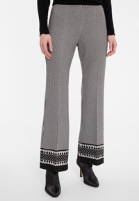 Schwarz-weiße Hahnentrittmuster-Hosen mit weitem Bein, versehen mit einem dekorativen schwarz-weißen Saum und glatter Textur.