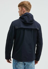 Granatowa, wodoodporna kurtka z kapturem, wentylacją z tyłu i zapięciem na zatrzaski. Charakteryzuje się gładką teksturą i luźnym krojem.