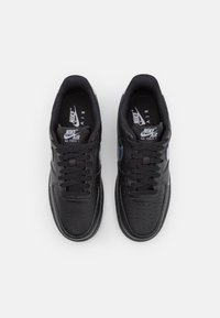 Ett par svarta Nike Air Force 1-sneakers sedd från ovan, som visar snörningen, perforerad tåbox och Nike-logotyp på tungan och innersulan.