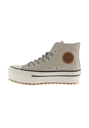 Beige højt oplagt sneaker med tyk hvid sål, sorte stribedetaljer, stribede snørebånd og rundt brunt logo patch på ankelsiden.