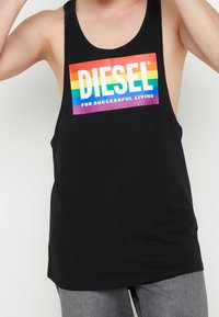 Svart bomullstopp utan ärmar med ett stort rektangulärt regnbågsgradientmönster och texten "DIESEL" och "FÖR FRAMGÅNGSRIKT LIV."