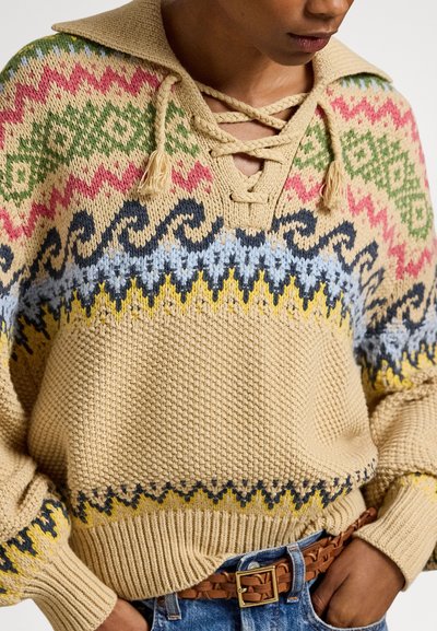 Πλεκτό πουλόβερ σε μπεζ με πολύχρωμα γεωμετρικά σχέδια σε κόκκινο, πράσινο, μπλε και κίτρινο. Διαθέτει λαιμόκοψη με δέσιμο και υφασμένα μανίκια.