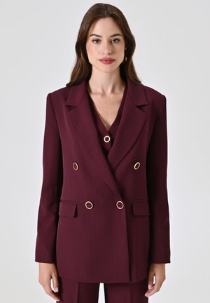 Blazer bordeaux doppiopetto con righe verticali, dettagli in metallo dorato e due tasche frontali. Vestibilità sartoriale con rever a lancia.